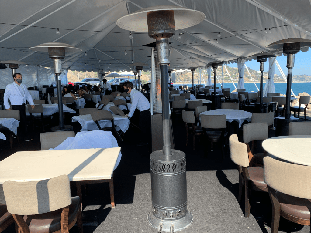 The tent that was set up due to the coronavirus pandemic (COVID-19), is the dining area currently for guests at Mastro's Ocean Club. Scott Gunderson (left) and Robert Livingston (right) are cleaning up before the guests arrive Sunday, Aug. 30, 2020, Malibu, California. (Photo/Chrissa Loukas)